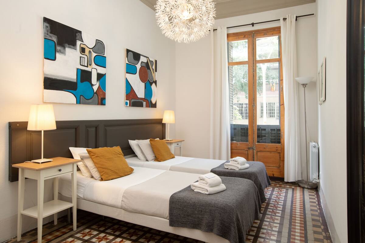 Habitación de hotel con dos camas, una puerta de madera y arte abstracto en las paredes.
