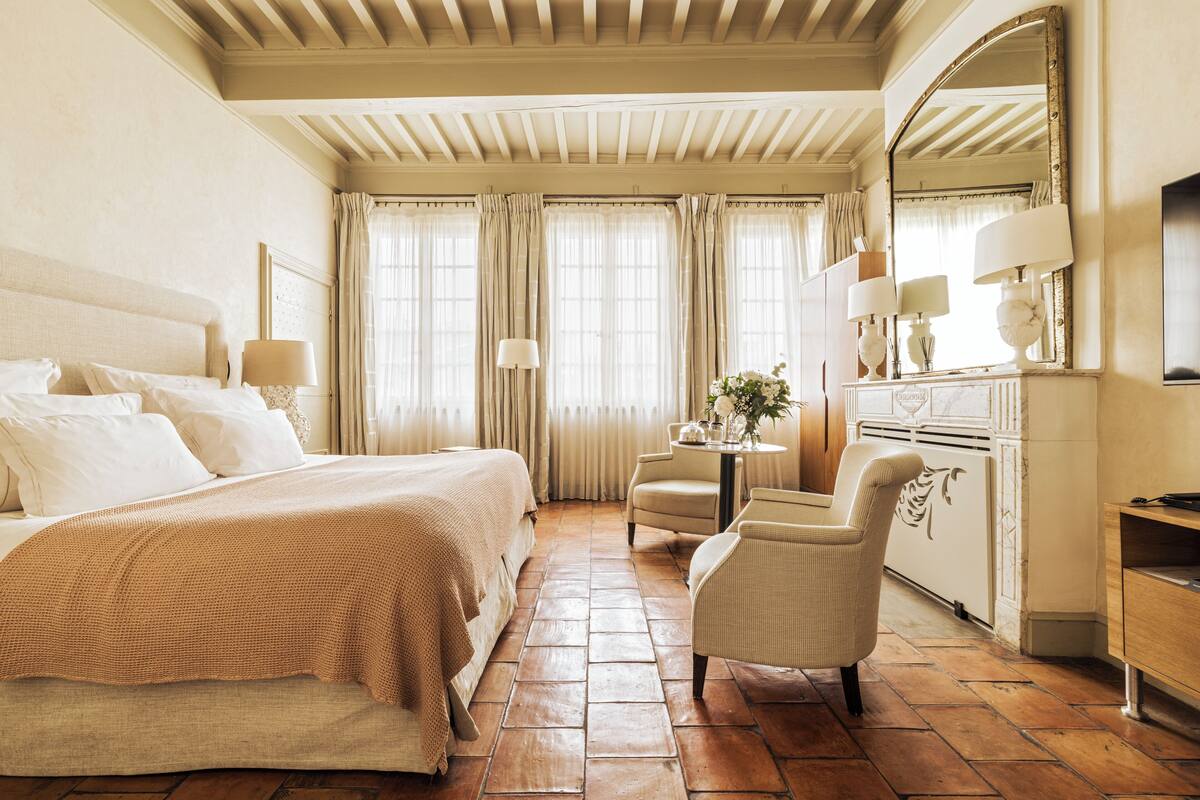 A hotel room with a large bed, a desk, a chair, a dresser, and a mirror.