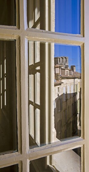 A window with a view of a building with multiple stories and a clear blue sky. - La Maison d'Uzes (Uzès)