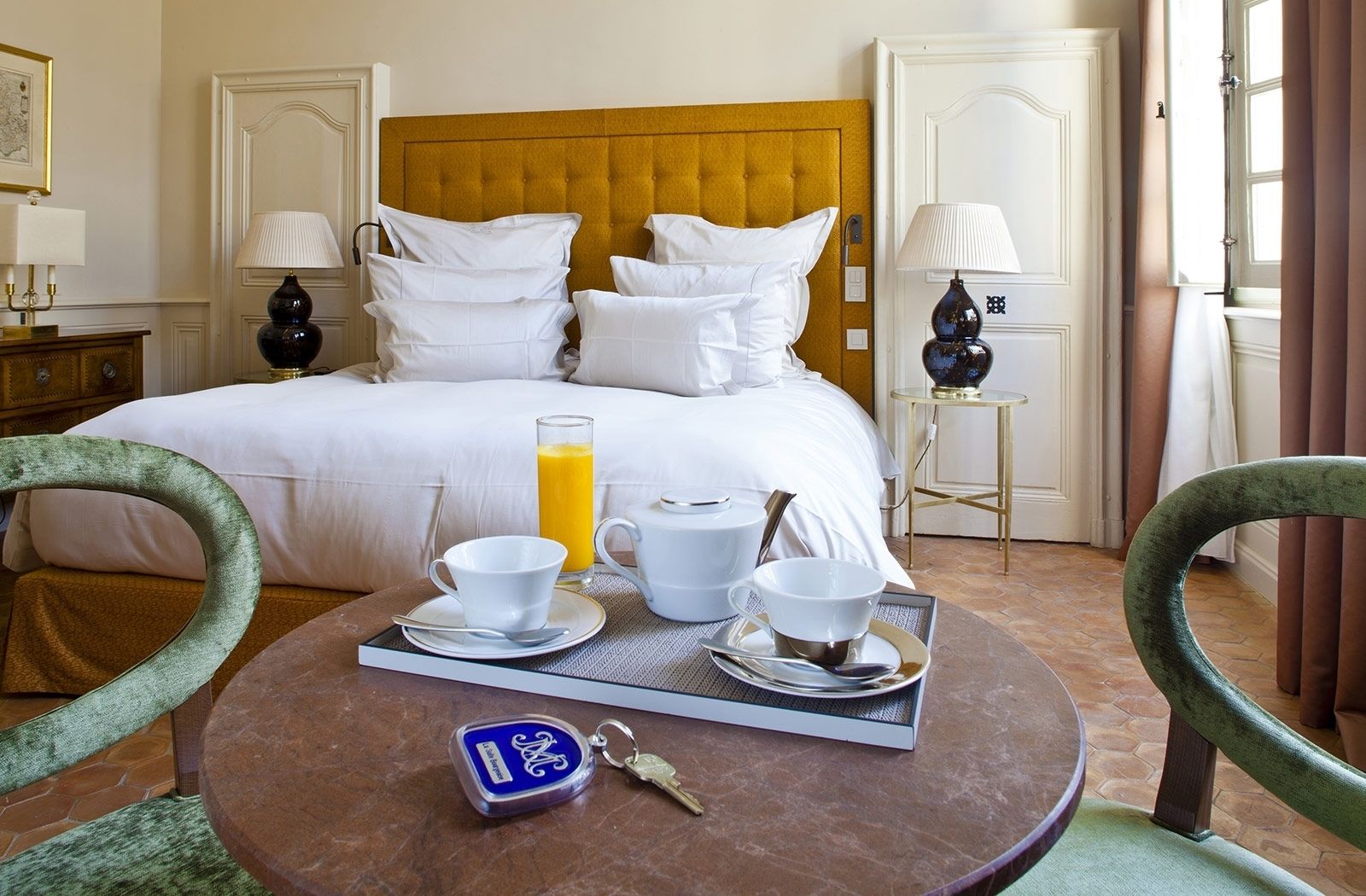 Une chambre d’hôtel avec un lit, un plateau de petit-déjeuner et une clé.