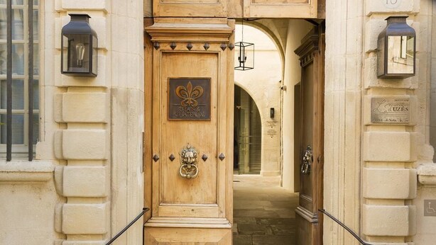 A wooden door with a plaque, a metal knocker, and a small window. - La Maison d'Uzes (Uzès)