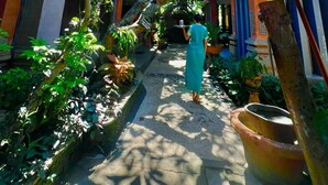 A narrow alleyway with traditional architecture, a person walking, and a large umbrella. - Ashyana Candidasa (Karangasem)
