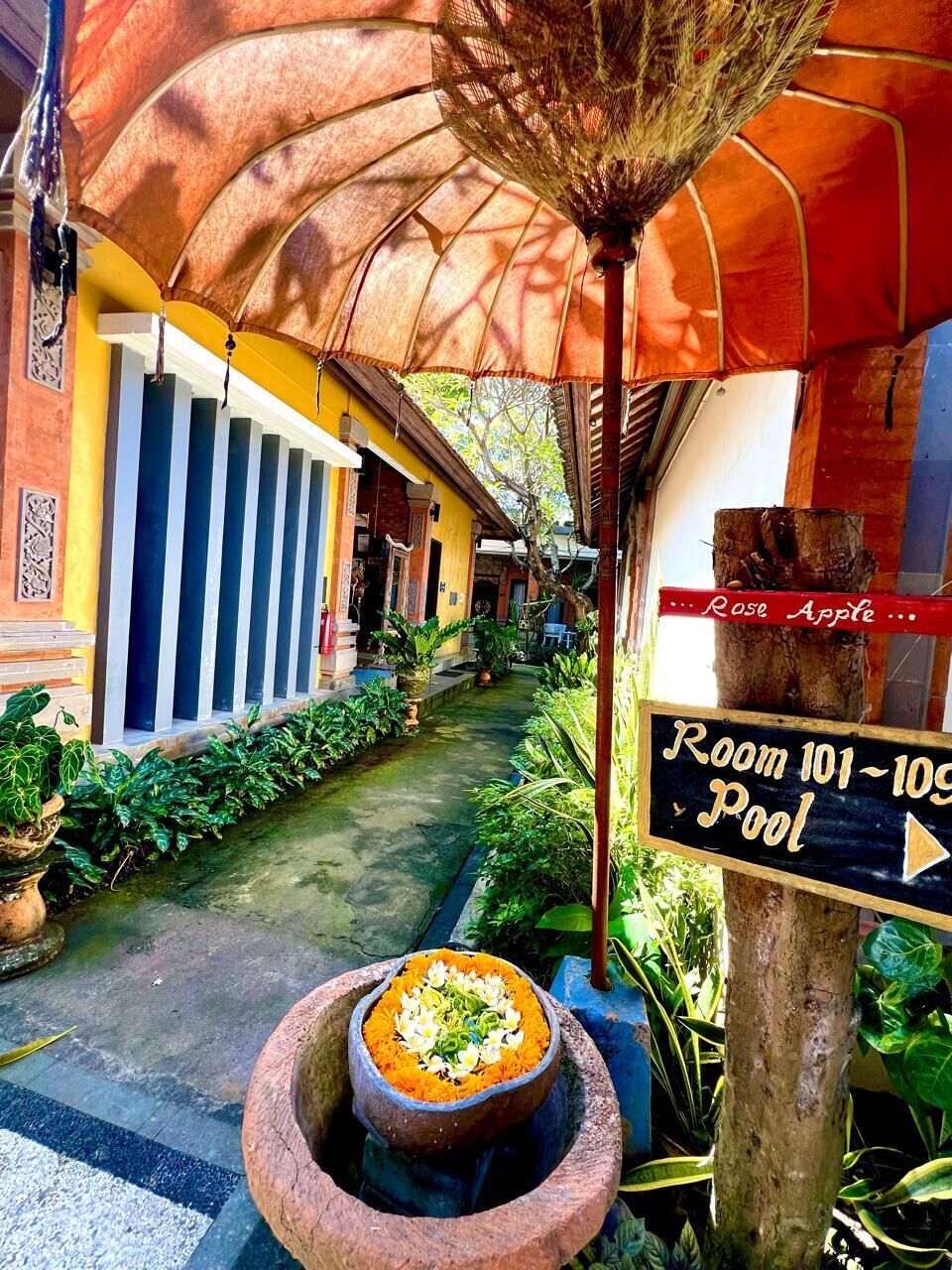A narrow pathway leading to a pool area, with a sign indicating 'Room 101-109 Pool.'