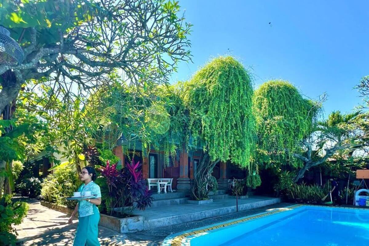 Una piscina con una banda amarilla de seguridad, rodeada de abundante vegetación y un cielo azul despejado.
