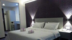 A hotel room with a large bed, two bedside lamps, a nightstand, and a small desk with a chair. - Muar Traders Hotel (Muar)