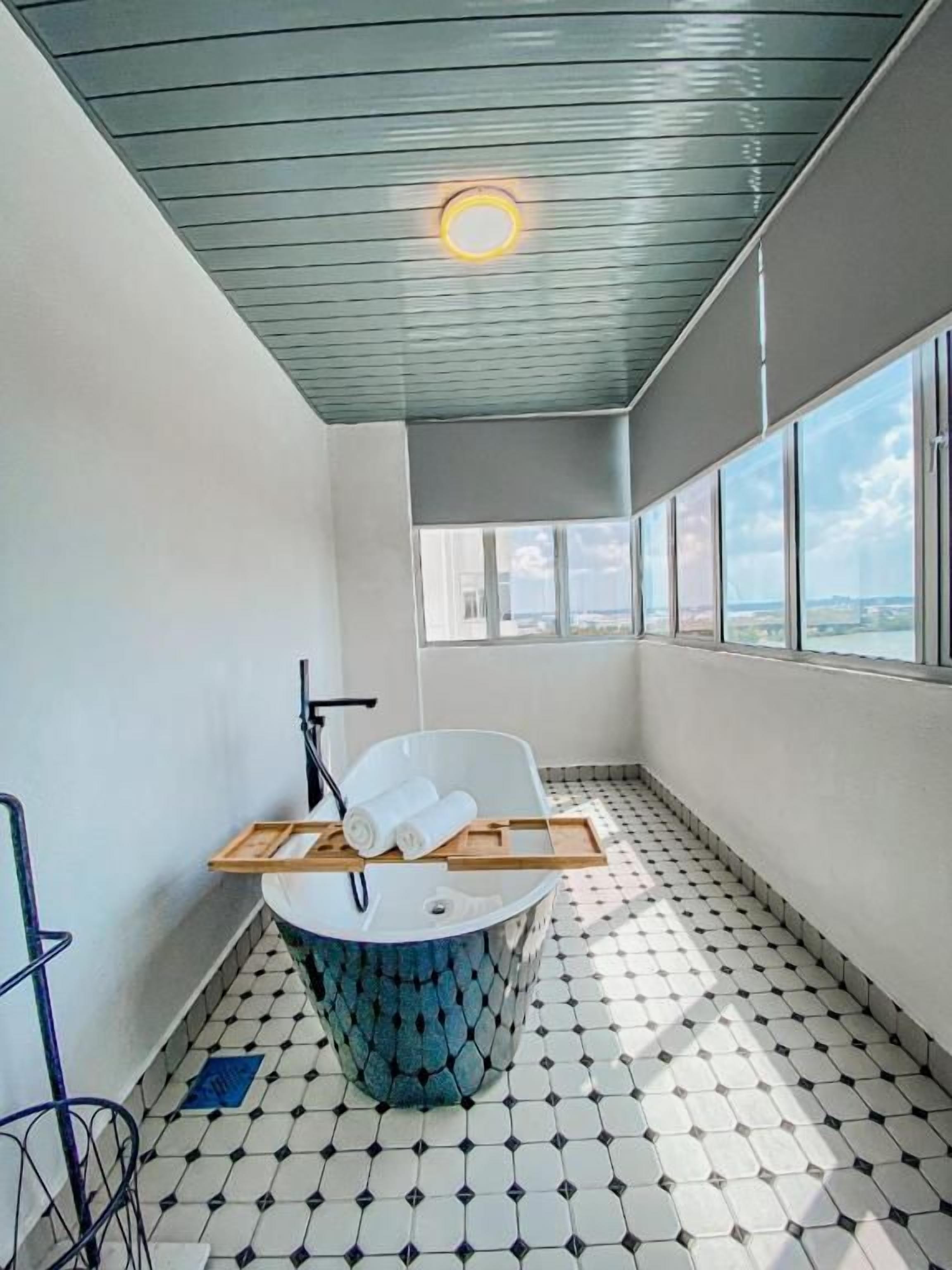 A modern bathroom with a bathtub, a towel rack, and a window providing a view of the cityscape.