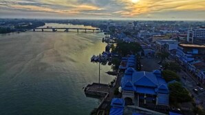 A river with a bridge, buildings, and a dock with boats. - Muar Traders Hotel (Muar)