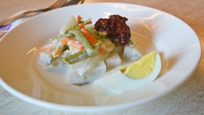 A white plate with a salad, a lemon wedge, and a dark condiment. - Muar Traders Hotel (Muar)