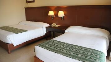 A hotel room with two single beds, a nightstand with a telephone, and two wall-mounted lamps.