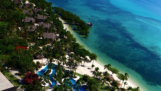 Un complexe hôtelier doté d’une plage, de palmiers et d’une piscine.