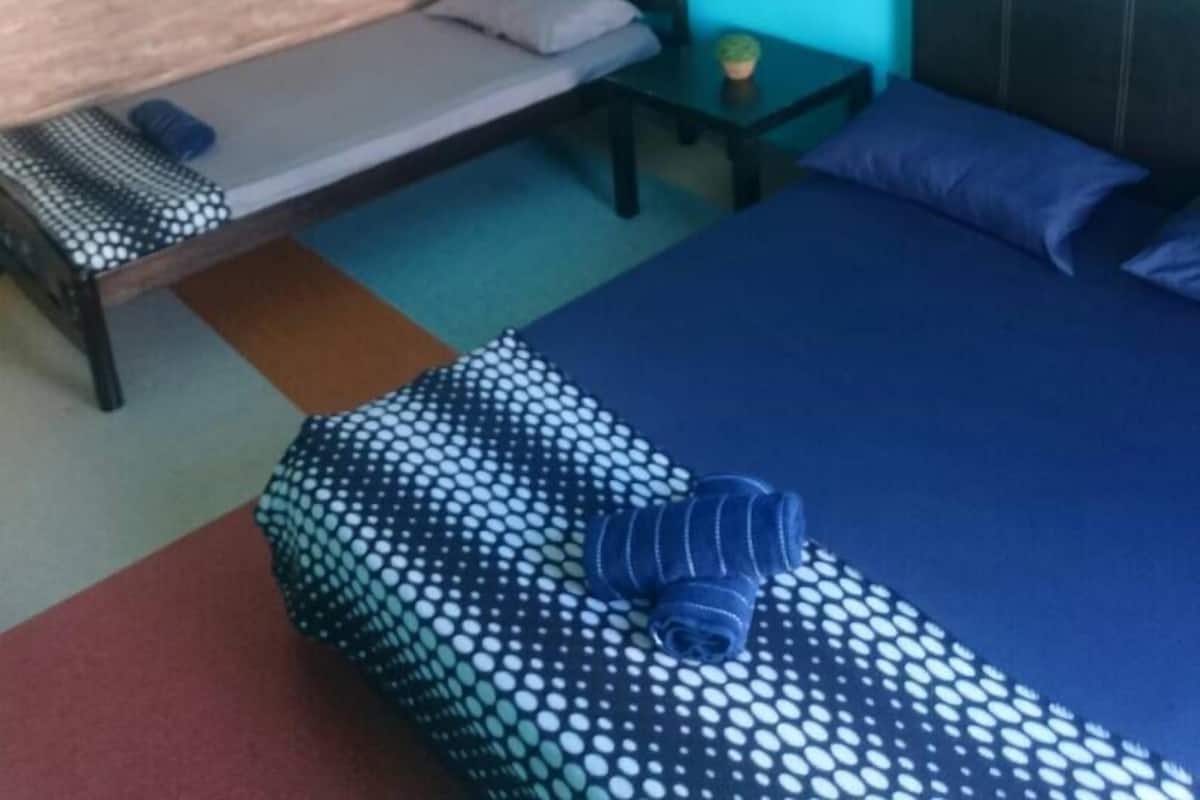 Un dormitorio con una cama, una mesita de noche, una pequeña mesa y una lámpara fijada a la pared.