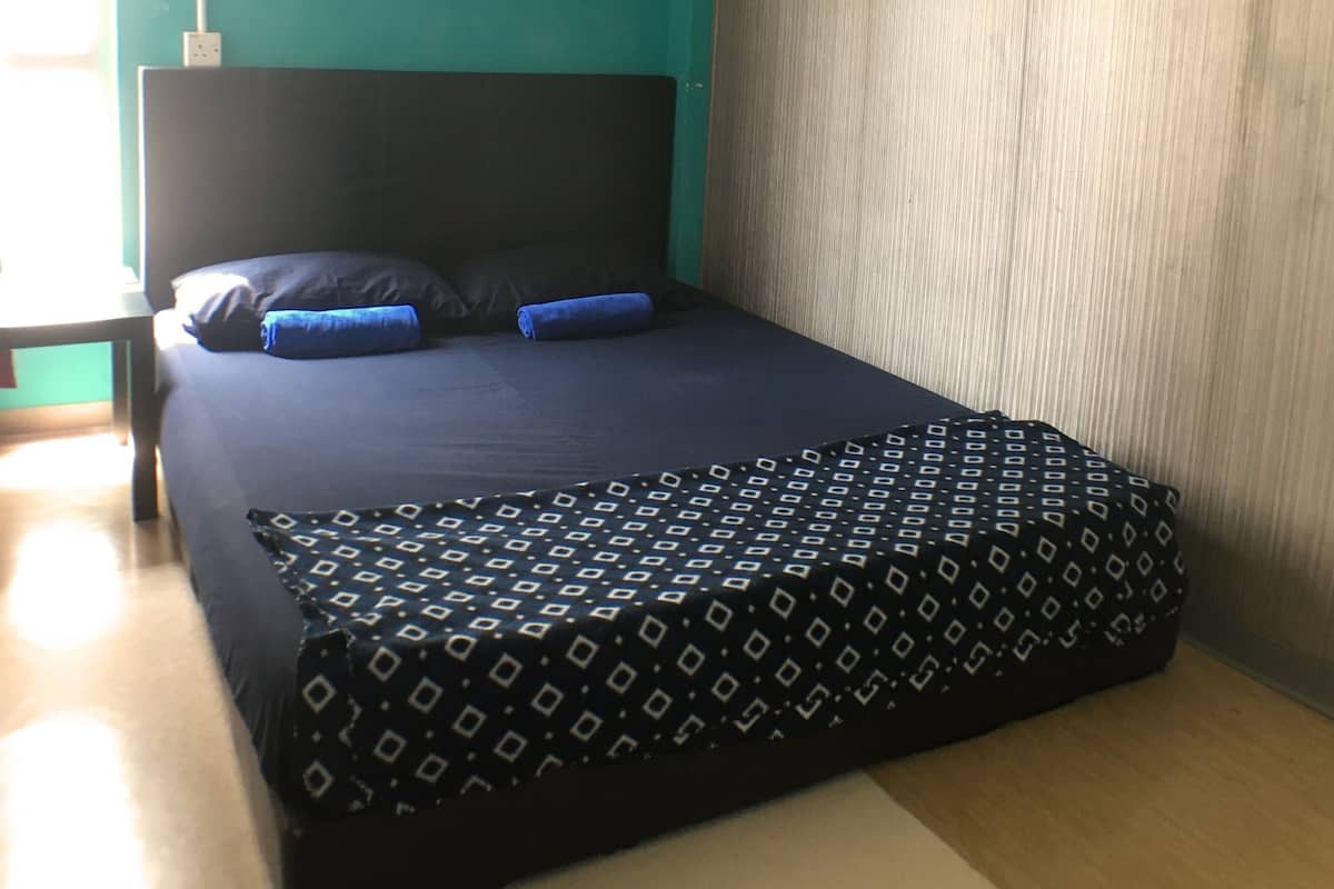 Un dormitorio con cama, cabecera, ventana, unidad de aire acondicionado y cortina.