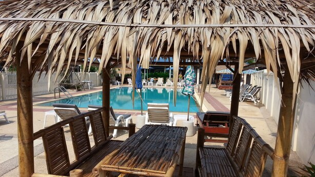 Uma área de piscina com móveis de bambu e uma estrutura de telhado de palha.