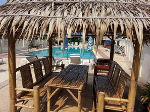 A poolside area with bamboo furniture and a thatched roof structure. - The Donkey's Rest (Hua Hin)
