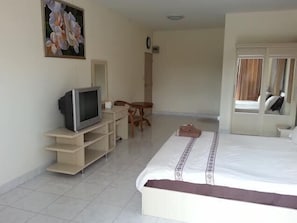 A hotel room with a bed, a television, a small table, and a chair.