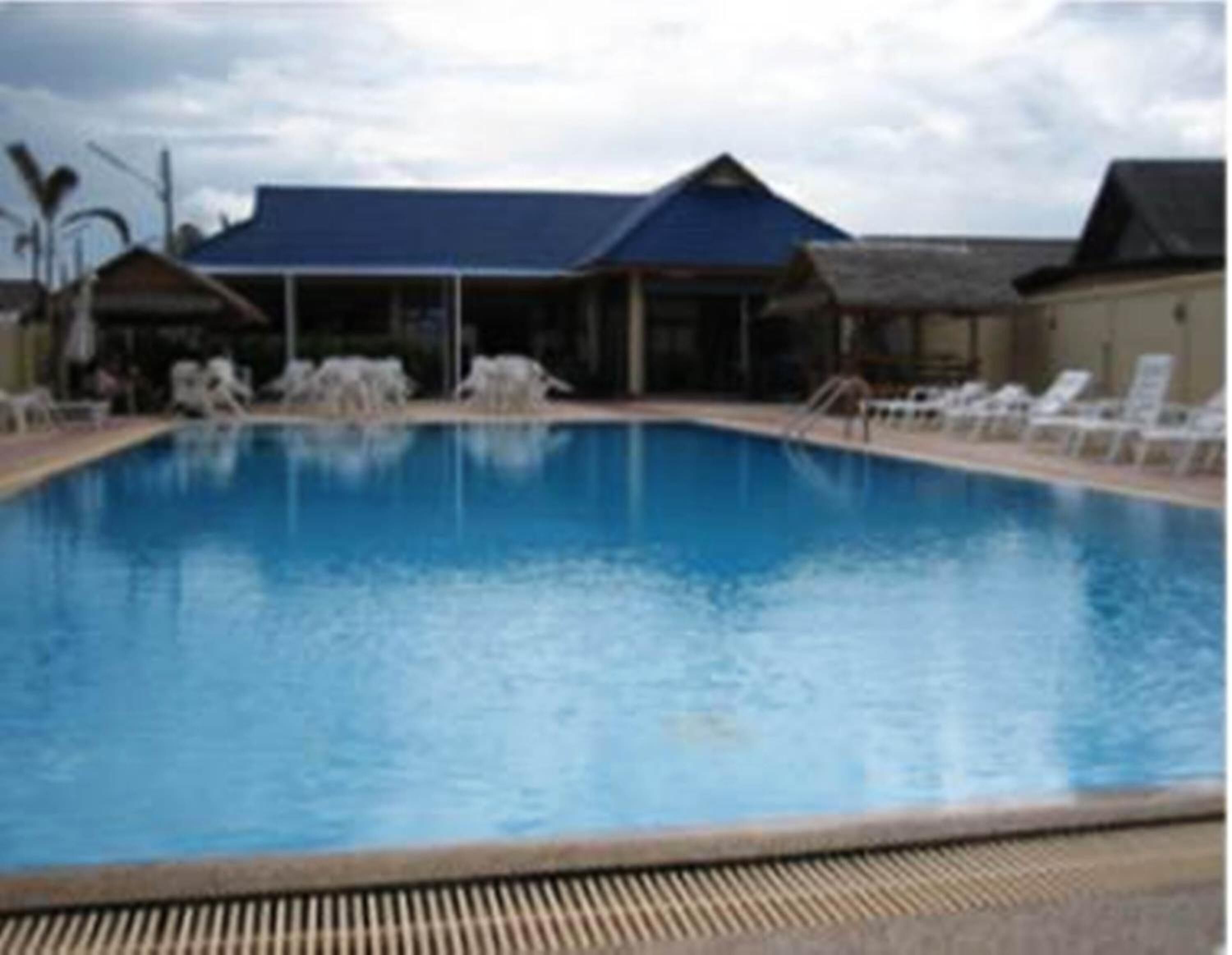 A swimming pool with lounge chairs and a covered area in the background.