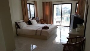 Quarto de hotel com cama, escrivaninha, cadeira e varanda com vista.