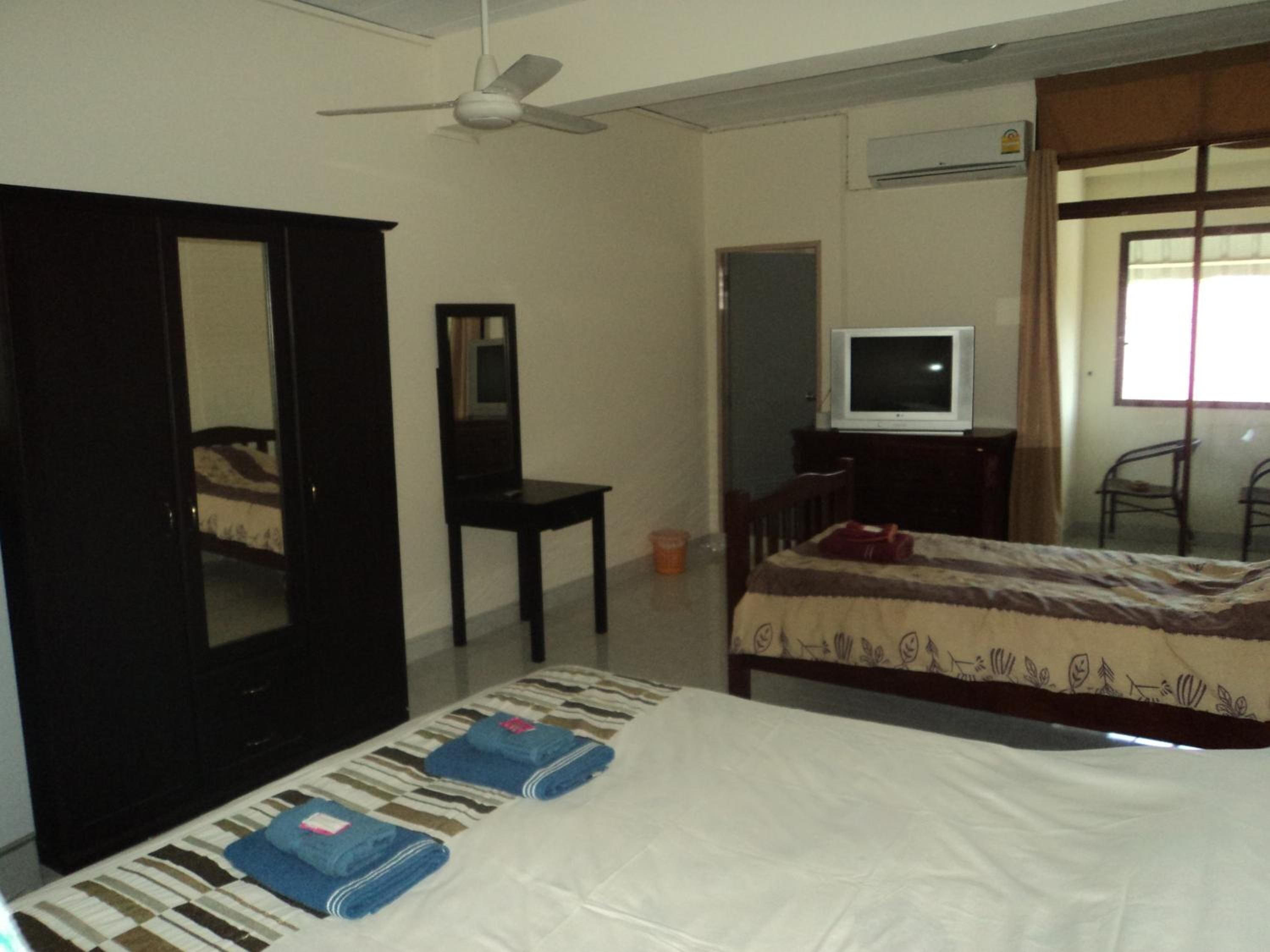 Une chambre à coucher avec un lit, une télévision, une armoire et un miroir.