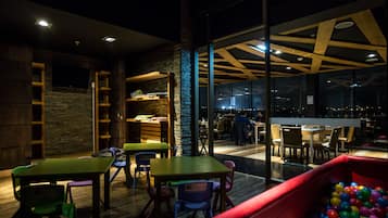 Enjoy meals in a spacious dining area with tables and chairs, a play area for kids, and city views.