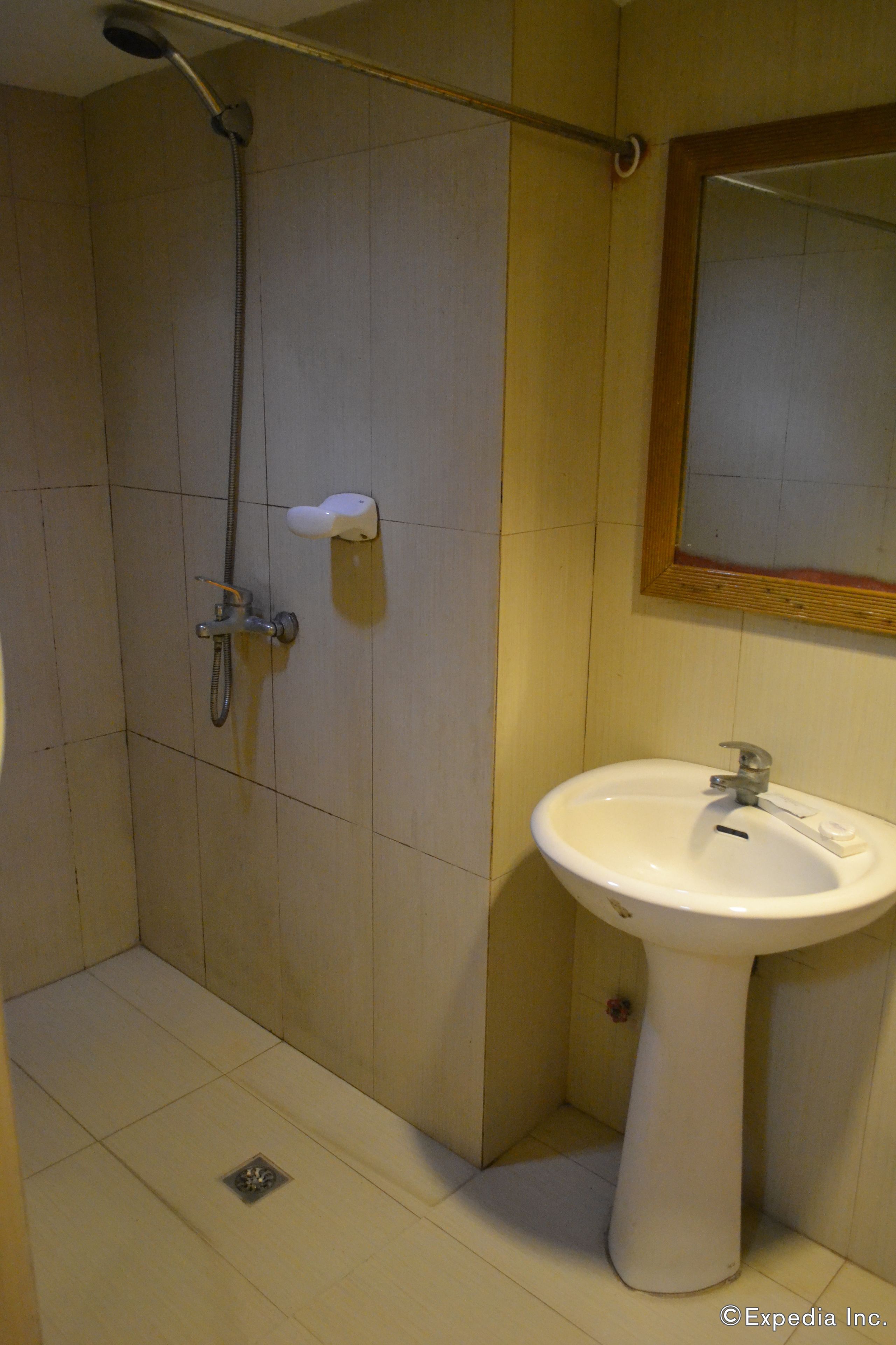 Un baño con ducha, lavamanos y espejo.