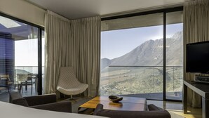Ein modernes Hotelzimmer mit großem Balkon, Flachbildfernseher und Bergblick.