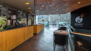 Ein modernes Restaurantambiente mit Holzbalkendecke, einer Rezeption und Blick auf eine verschneite Landschaft durch große Fenster.
