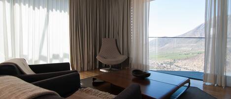 A modern living room with a view of a mountainous landscape through large windows.