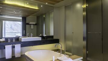 A modern bathroom with a large bathtub, a vanity with a mirror, and a shower area.