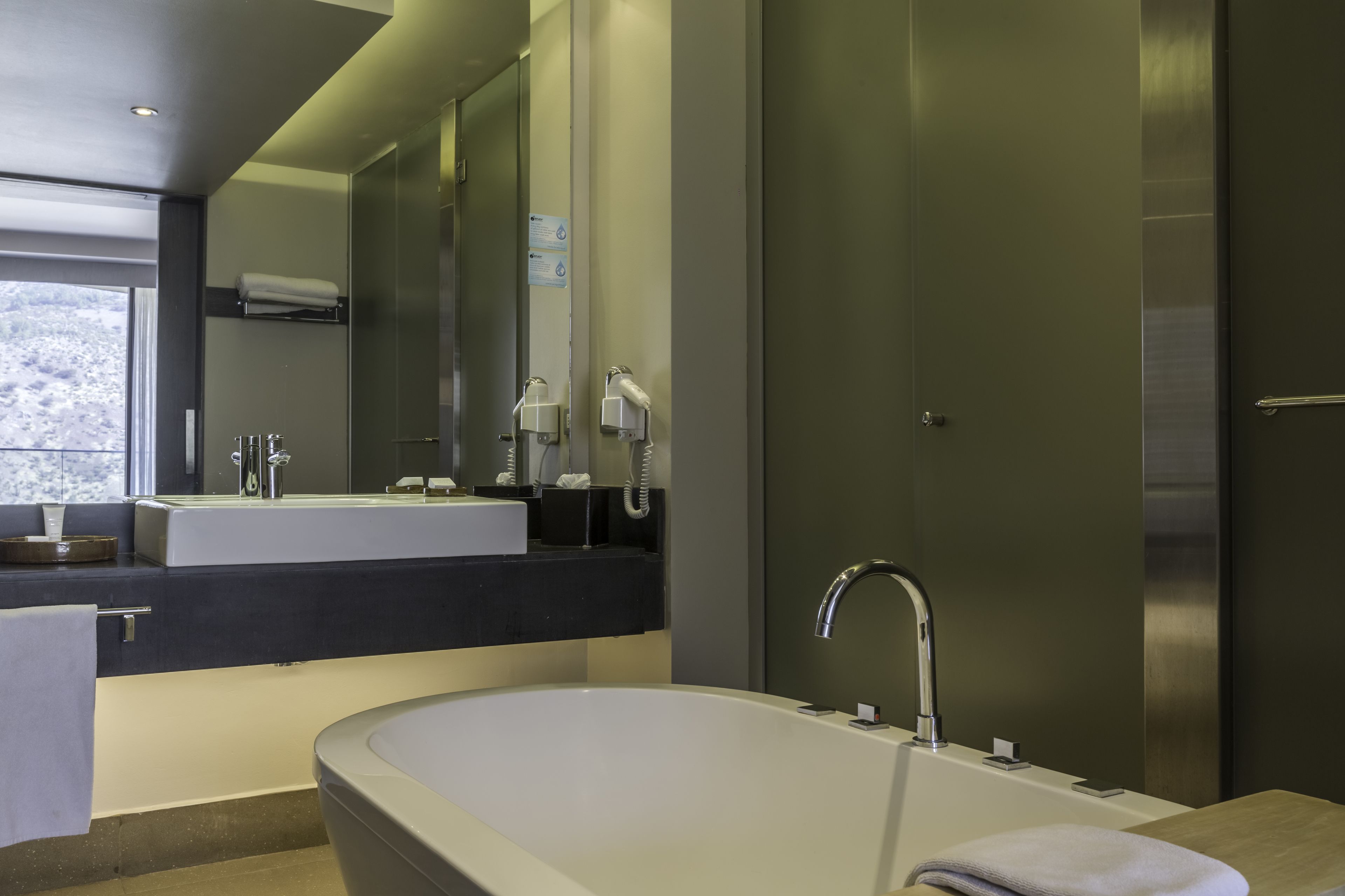 Une salle de bain moderne avec une grande baignoire, un lavabo et un miroir.