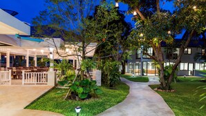 A well-maintained outdoor area with a concrete pathway, seating arrangements, and lush greenery. - Prinz Garden Villa Hua Hin (Hua Hin)