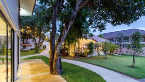 A well-maintained outdoor area with a pathway leading to a building, surrounded by greenery and trees. - Prinz Garden Villa Hua Hin (Hua Hin)