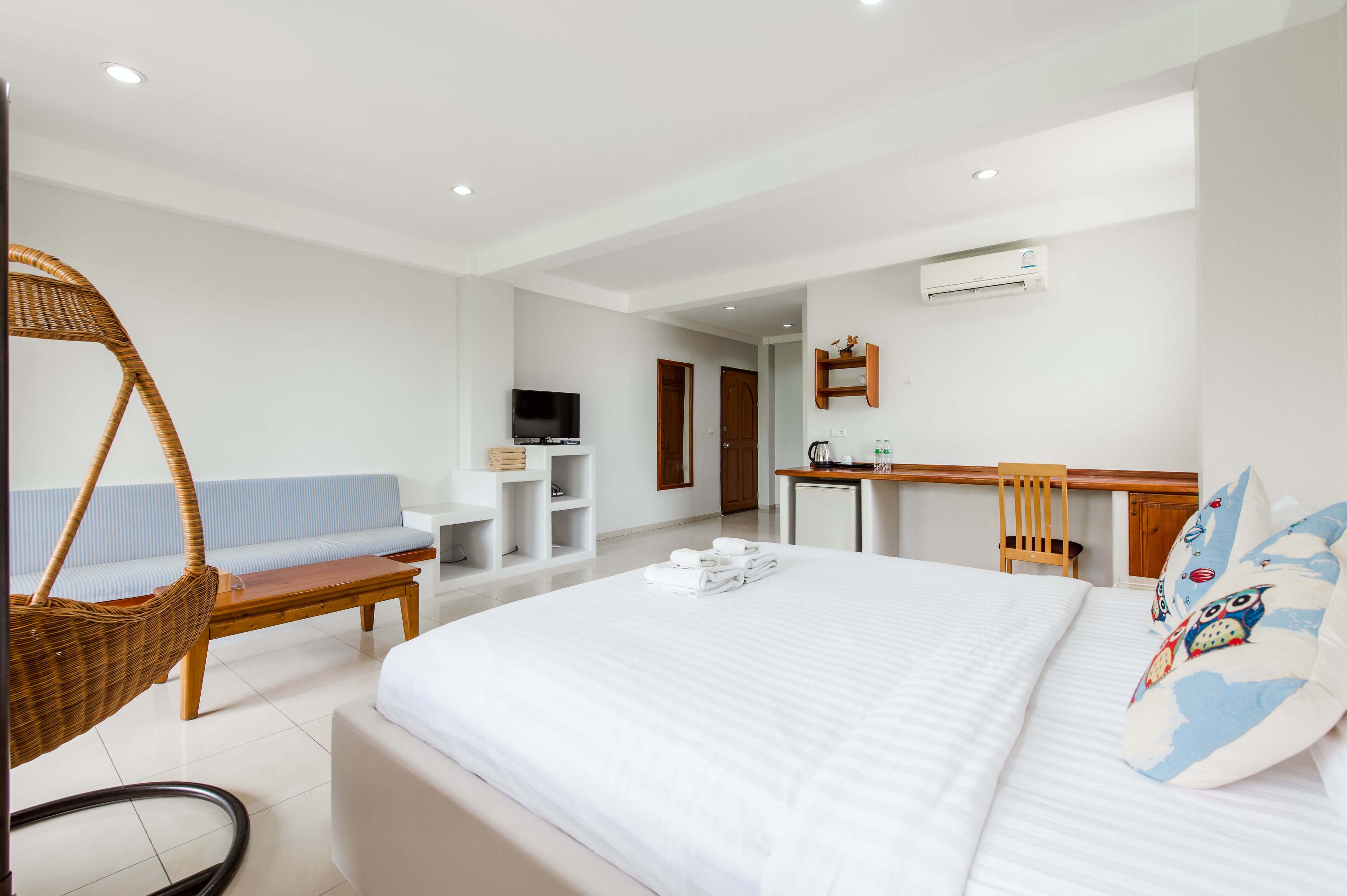 A modern hotel room with a large bed, a sofa, a desk, and a television.