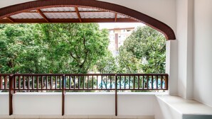 A balcony with a wooden railing, white walls, and a view of greenery and buildings. - Prinz Garden Villa Hua Hin (Hua Hin)