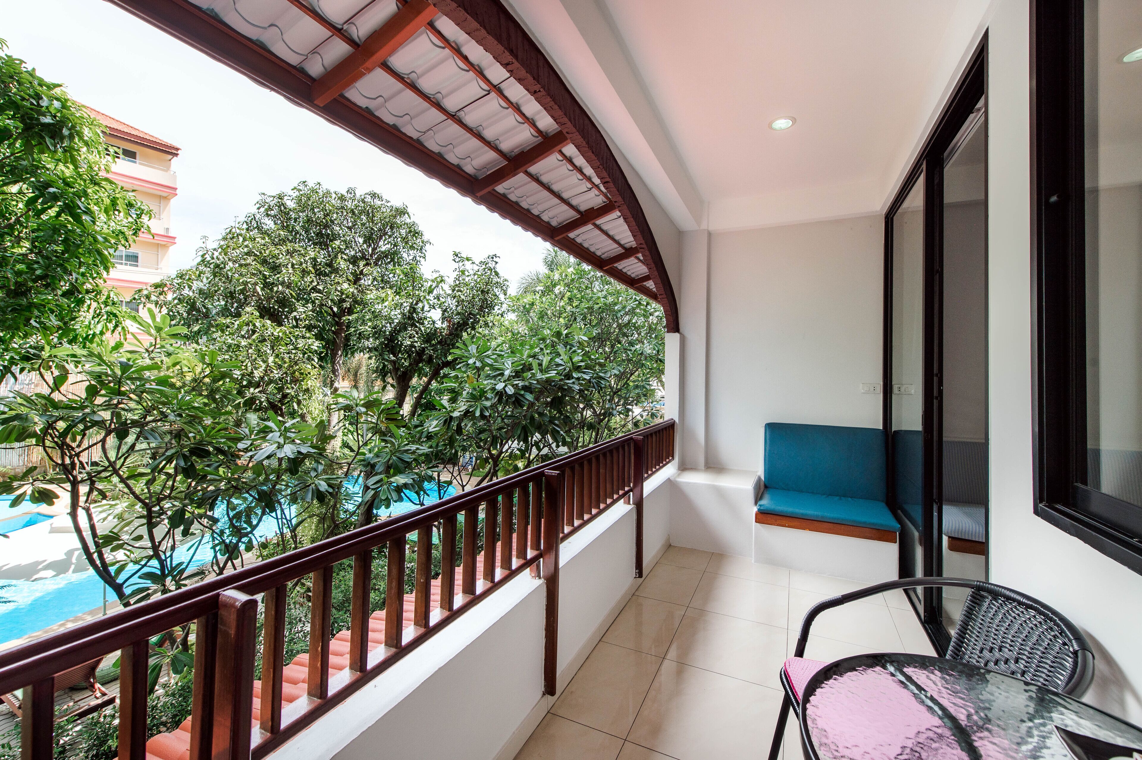 A balcony with a view of a swimming pool, a blue cushioned bench, and a table with chairs.