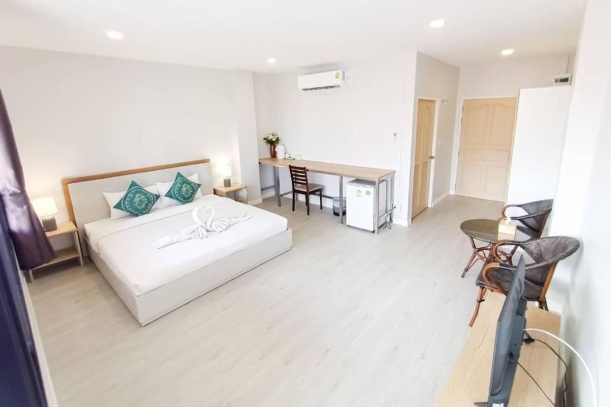 A bedroom with a bed, a desk, a chair, and a TV.