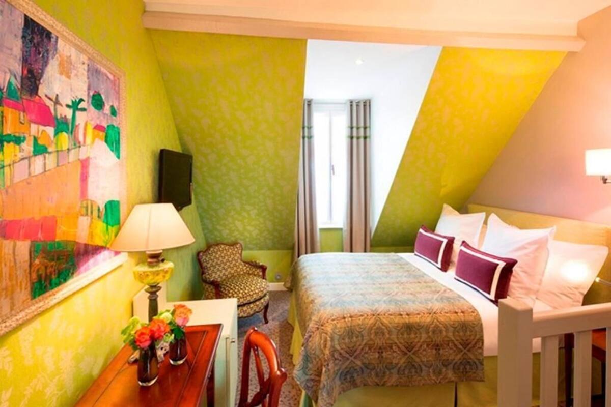 A room with a bed, a chair, a desk, a lamp, and a painting on the wall.