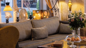 A cozy living room with a sofa, decorative lamps, and a vase with flowers. - Le Relais des Halles (Paris)