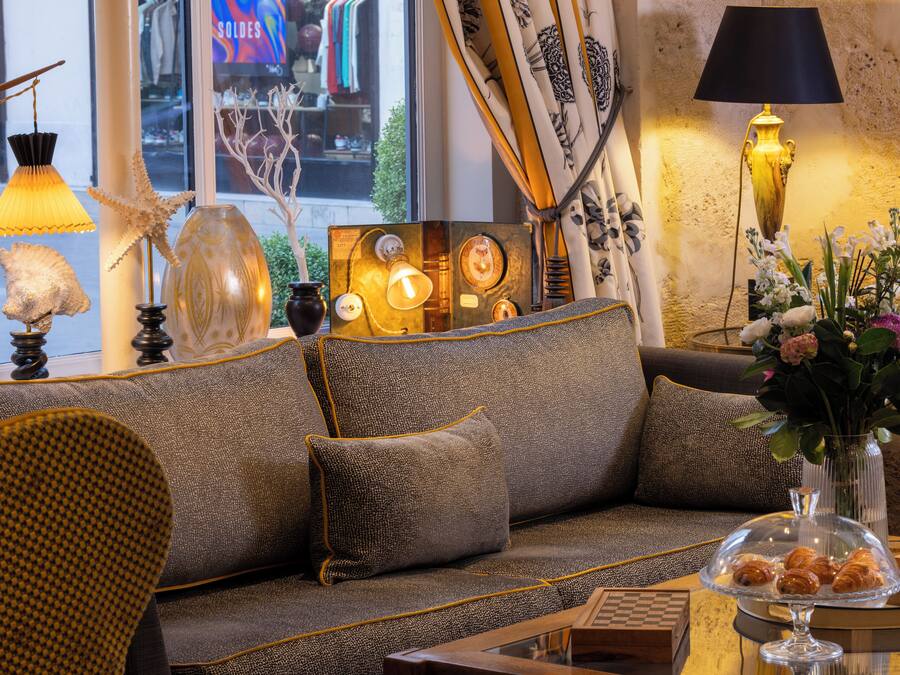 Una sala acogedora con un sofá, lámparas decorativas y un florero con flores.