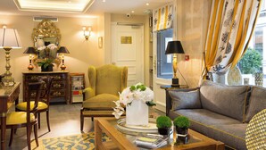 A well-lit living room with a sofa, chairs, a coffee table, and a decorative mirror. - Le Relais des Halles (Paris)