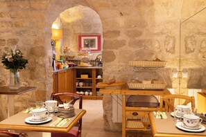 A cozy café with stone walls, wooden furniture, and a variety of baked goods displayed on shelves and tables. - Le Relais des Halles (Paris)