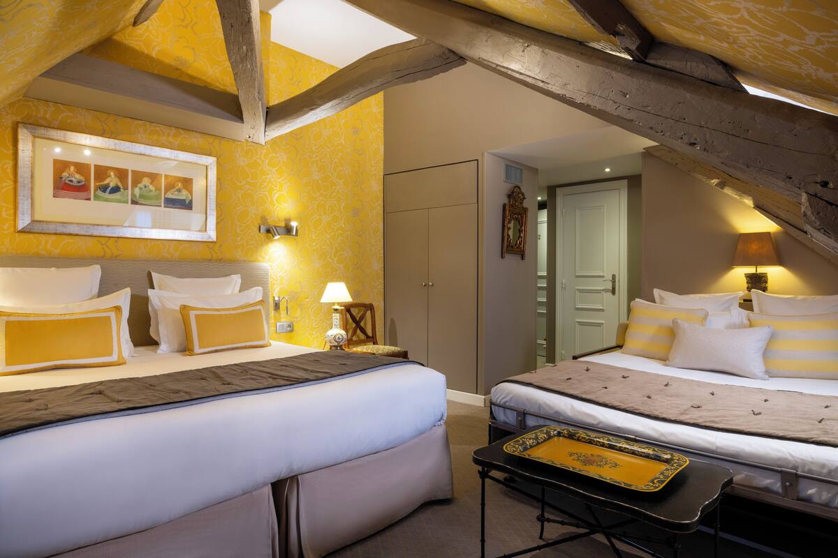 A hotel room with two beds, a wooden ceiling, and a framed picture on the wall.
