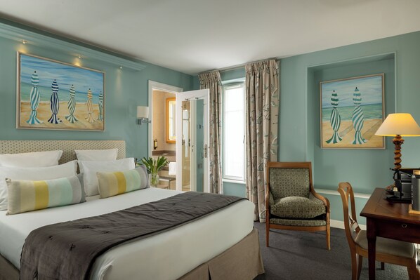A hotel room with a bed, a chair, a desk, and two paintings on the walls. - Le Relais des Halles (Paris)