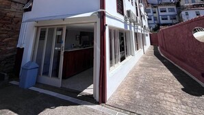 A building with a white facade, a red roof, and a stone wall on the left. - Pousada Casa dos Contos (Ouro Preto)
