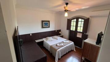 Een kleine, eenvoudige kamer met een bed, een bureau en een kledingkast.