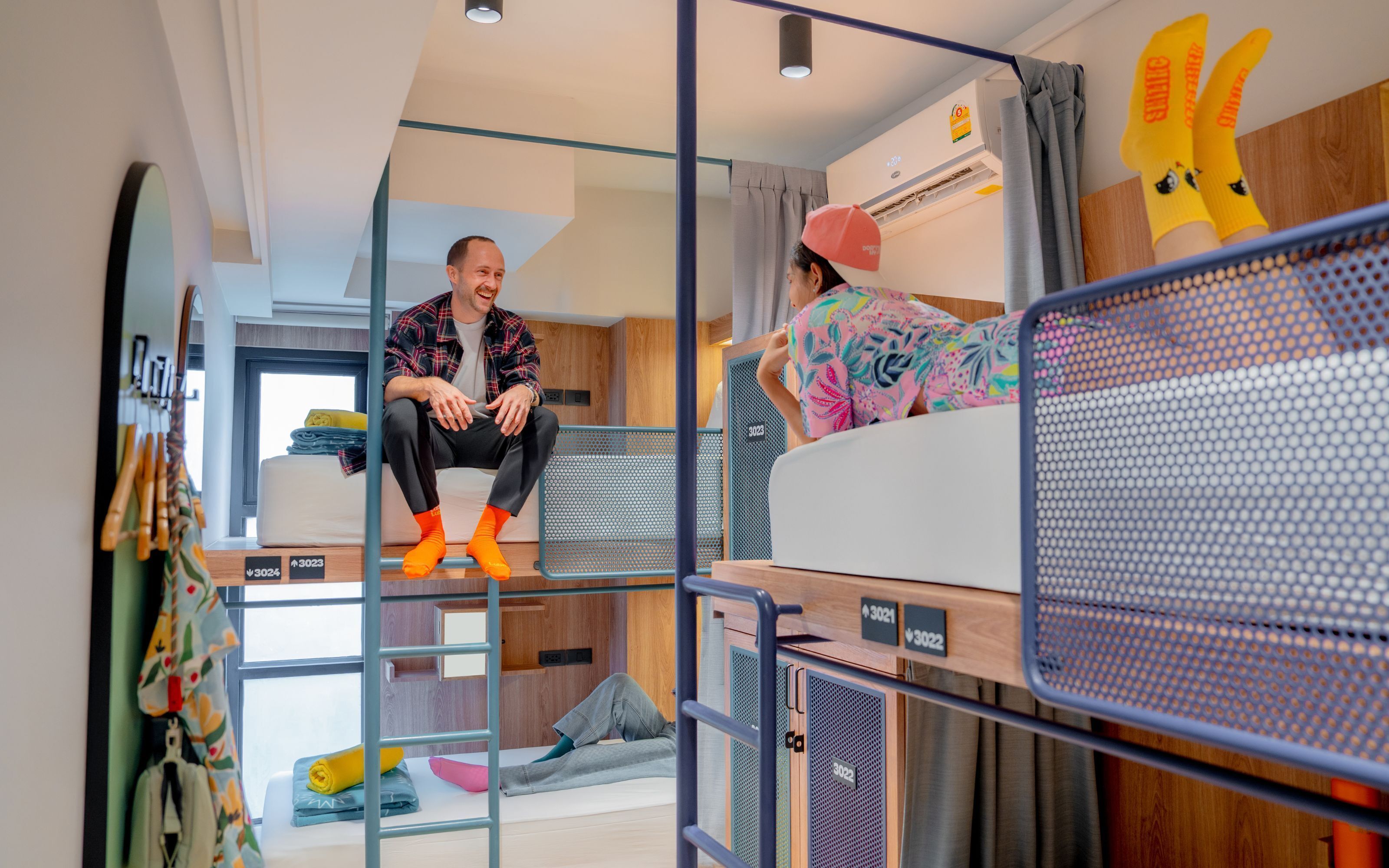 A modern, compact room with bunk beds, a small kitchenette, and a window providing natural light.