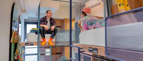 A modern, compact room with bunk beds, a small kitchenette, and a window providing natural light.