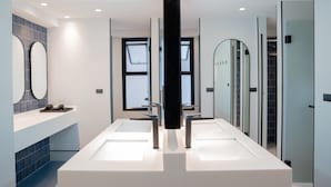 A modern bathroom with two sinks, a large mirror, and a glass shower enclosure.