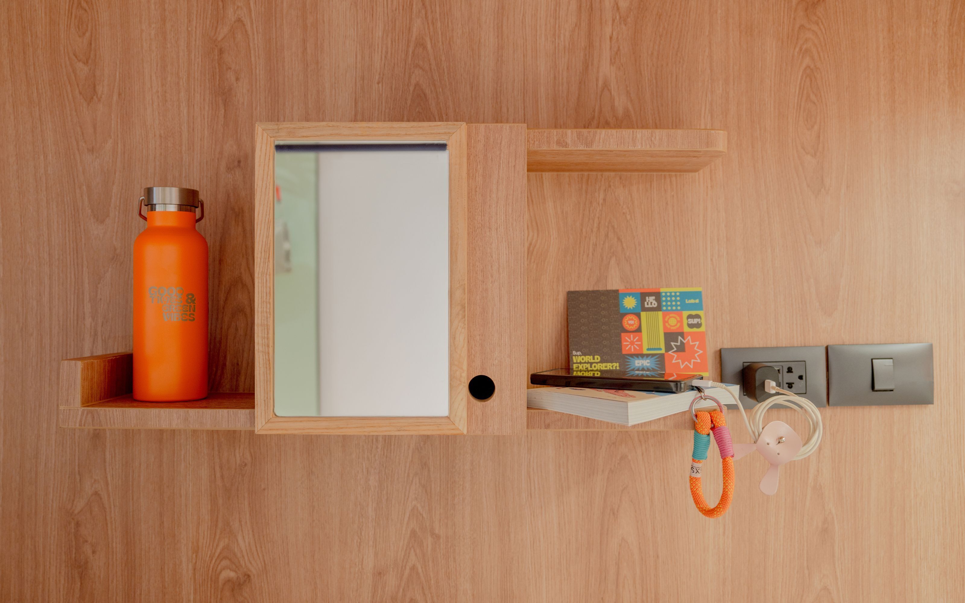 Pared de madera con una pizarra, una botella de agua, un libro y un enchufe.