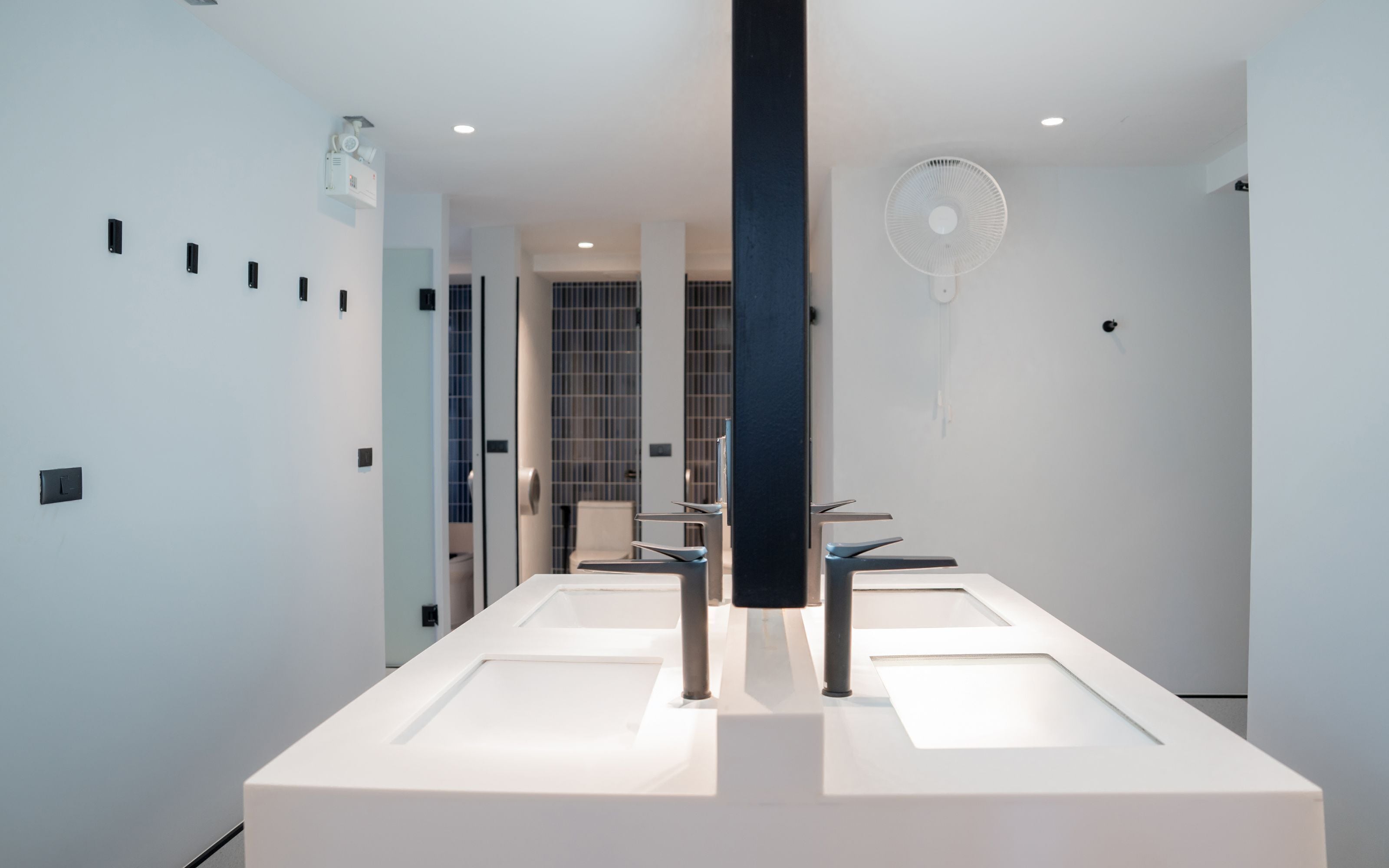 A modern bathroom with two sinks, a large mirror, and a ceiling fan.
