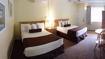 Une chambre d’hôtel avec deux lits, une petite table et une chaise.